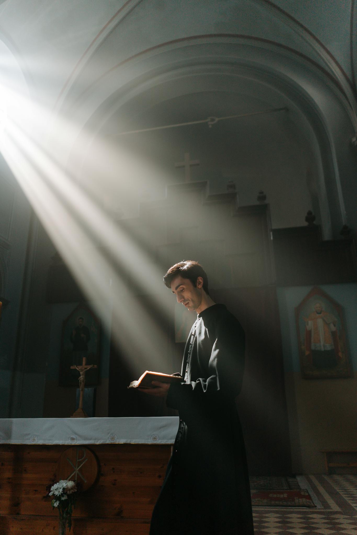 A priest stands reading a bible in a sunlit church, symbolizing faith and spirituality.